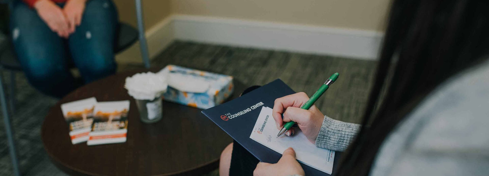 someone writing on a notepad in consoling session