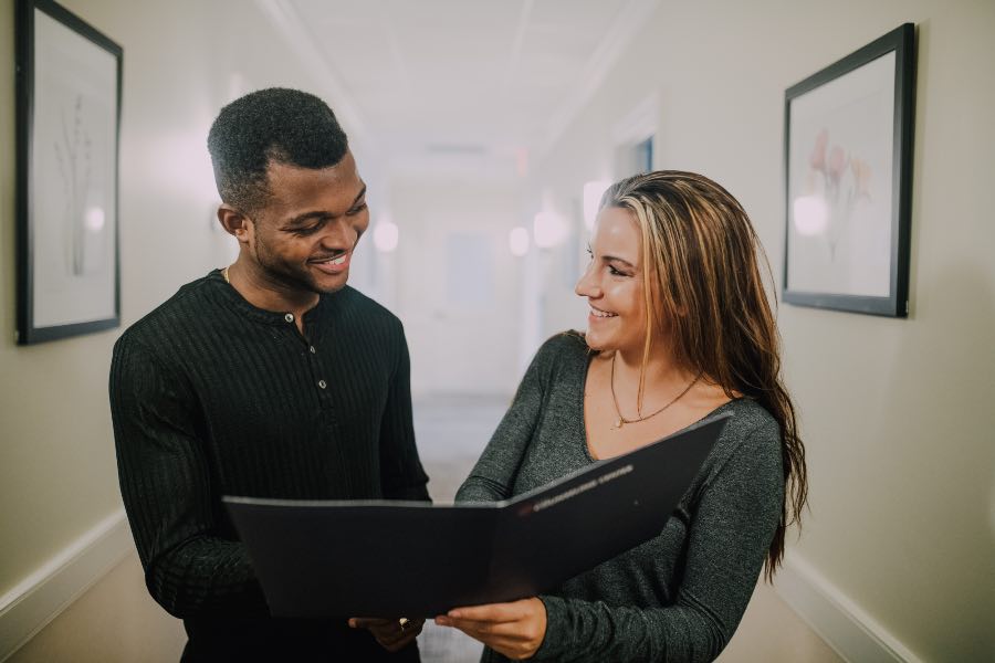 man and woman talking looking at notepad
