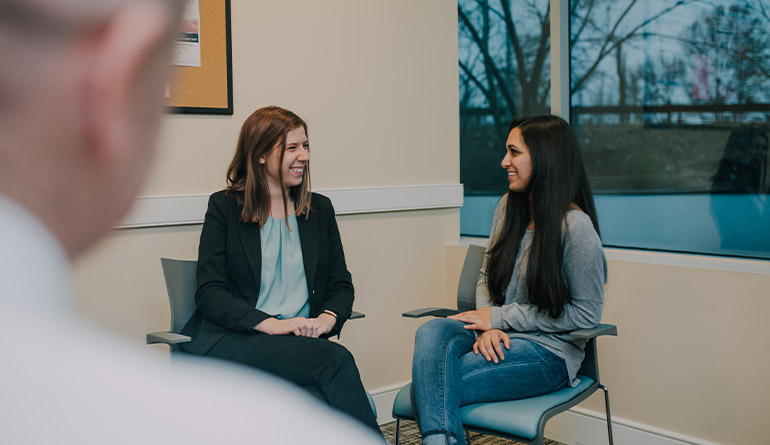 two women sitting down smiling and talking