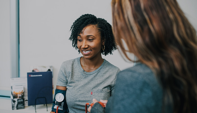 a woman checking another woman's blood pressure